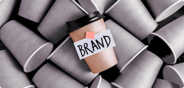 Vaso de café con el texto Brand destacando entre otros vasos sin branding