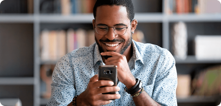 Hombre mirando su celular mientras sonríe mientras aprende sobre qué es un hashtag