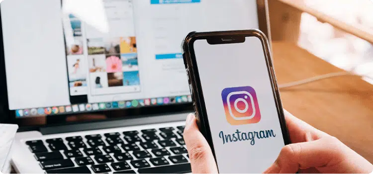 Manos de una persona sosteniendo su celular con la pantalla de inicio de Instagram