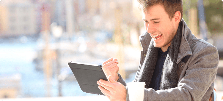 Hombre celebrando frente a su tablet en referencia a su alegría por el aumento de las ventas de su negocio