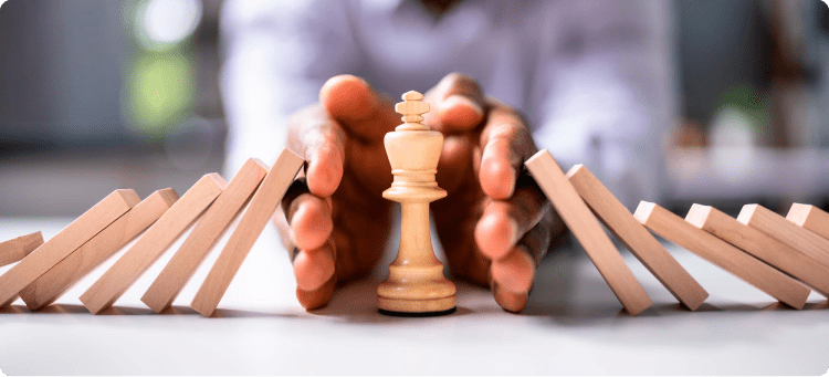 Ficha de ajedrez protegida por las manos de una persona para que no le caigan fichas encima en referencia a los desafíos que enfrenta la industria de los seguros que un CRM puede ayudar a enfrentar