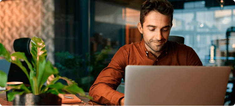 Hombre trabajando sonriente en su computador en referencia a las herramientas para gestionar redes sociales