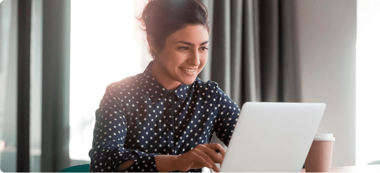 Mujer sonriendo mirando la pantalla de su computador en referencia a las razones de por qué se necesita una landing page para eventos