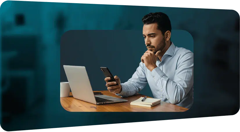 Ejecutivo revisando WhatsApp desde su celular junto a su laptop para gestionar clientes con un CRM